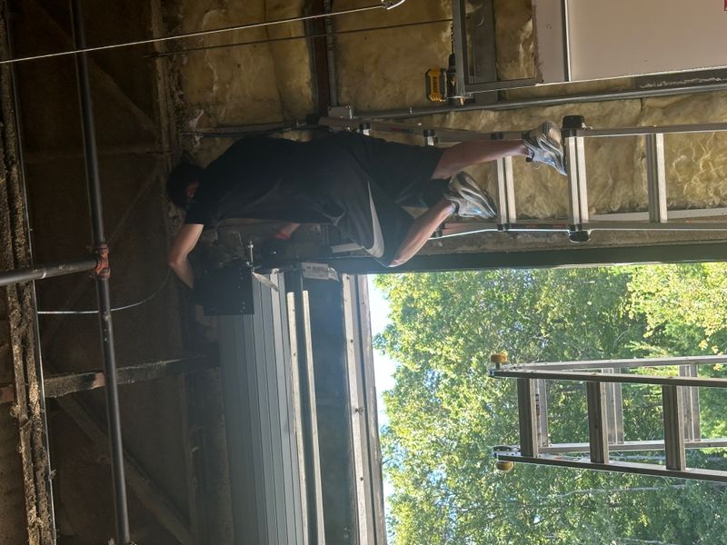 Technician installing commercial overhead door from ladder in Massachusetts warehouse