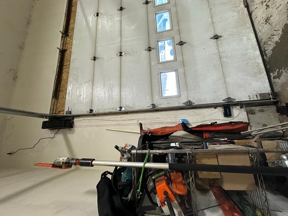 Interior angle of commercial sectional door with vertical windows and opener rail — Massachusetts