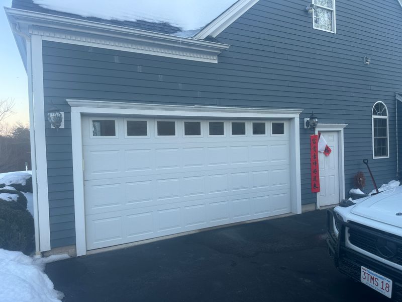 White double garage door with top windows on blue colonial home in Massachusetts winter
